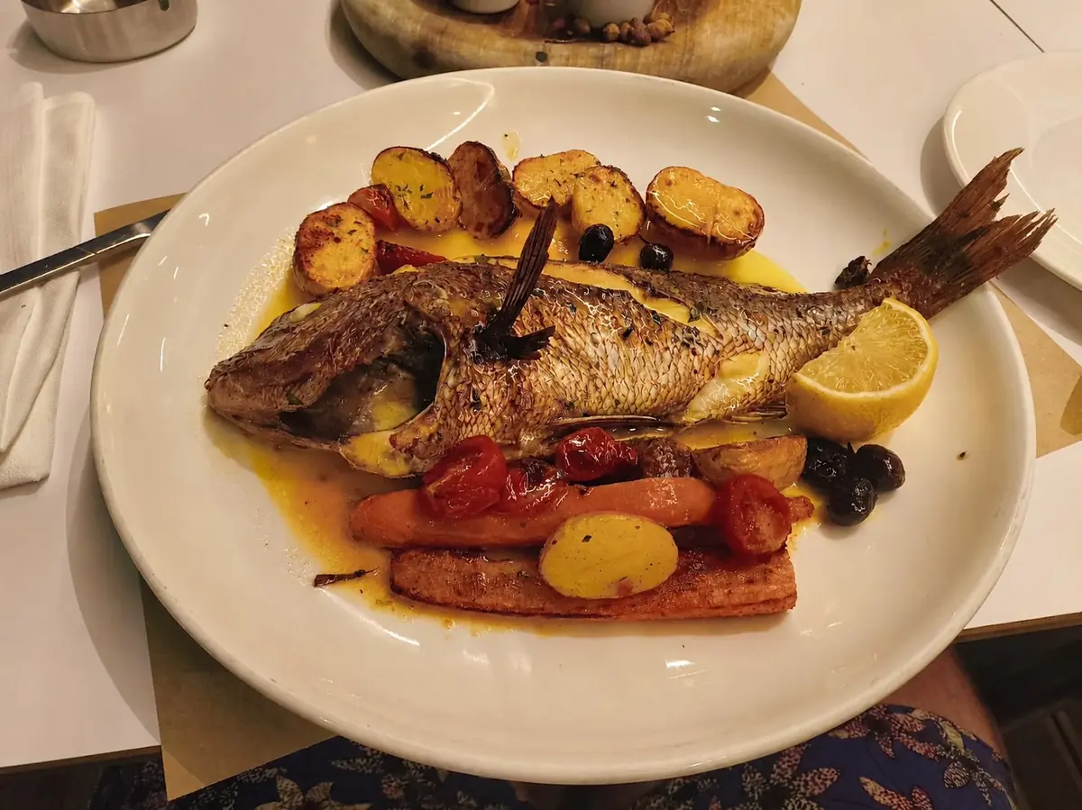 Whole roasted fish with potatoes, vegetables and lemon